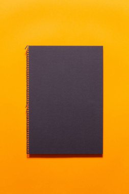 Siyah çarşaf, parlak turuncu arka planda defterinden yeni koparılmış. Düz yatıyordu.