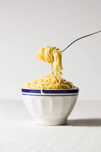 Widelec Pasemkiem Spaghetti Zawieszonym Nad Miską Pełną Spaghetti — Zdjęcie stockowe