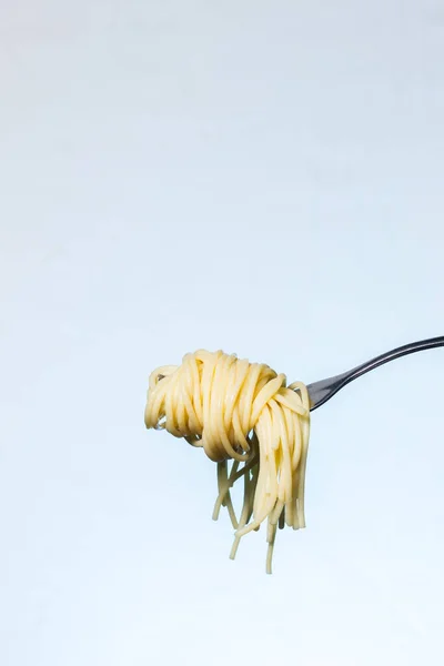Zdjęcie Boczne Widelca Pasemkiem Spaghetti Zawieszonym Jasnym Teksturowanym Tle — Zdjęcie stockowe