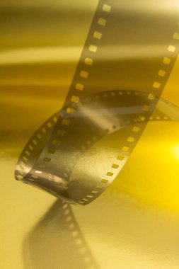 Fragment of 35 mm movie suspended on a golden surface. Cinematographic success concept.