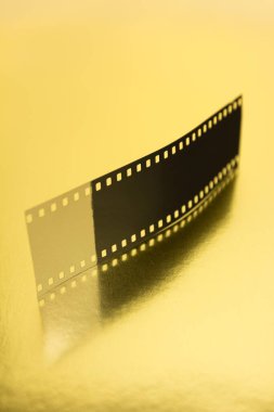 Fragment of 35 mm film on golden surface. Cinematographic success concept.