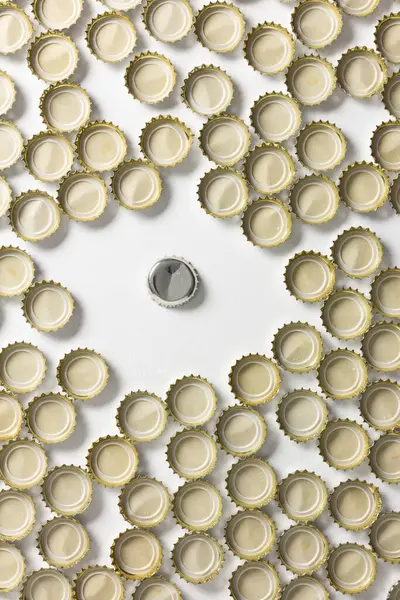 Soda bottle caps facing upwards surround a different one facing downwards. Unique and special concept.