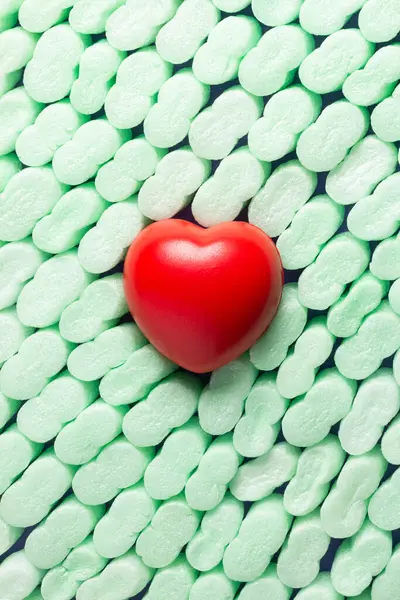 Deep red heart on green styrofoam pieces arranged in an orderly fashion. Concept of heart protection and general health.