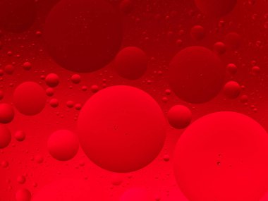 Göze çarpan soyut bir görüntü, suyun üzerine canlı kırmızı yağ damlaları, canlı ve dinamik arka planlar için ideal..