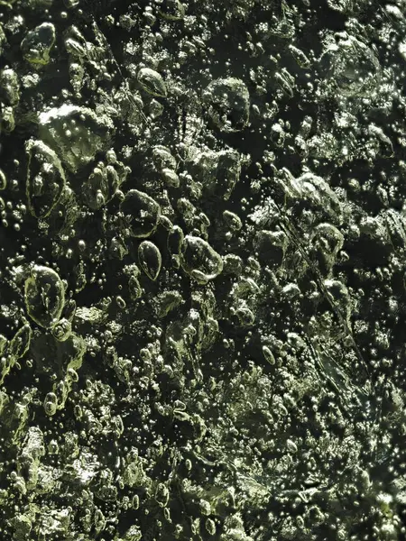 Kabarcıklı, karanlık bir buz dokusunda ışıl ışıl bir güneş ışığı..