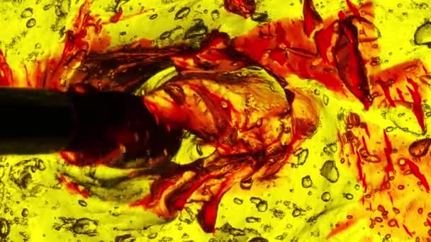画家的画笔进入画框 用饱和的黄色背光在发泡的凝胶表面混合了强烈的红色颜料滴 — 图库视频影像