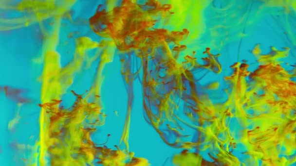 フレームは青い水に赤と黄色のインクのトレイルの魅惑的なダンスで満たされ 各滴のパスは複雑な水生タペストリーに追加されます — ストック動画
