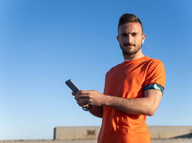 Genç sporcu, spor yaptıktan sonra akıllı telefon uygulamasını kontrol ediyor, fitness izleme ve sağlık izleme teknolojisini benimsiyor.
