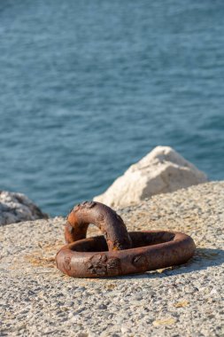 Arka planda deniz olan dalgalı bir dalgakıranda demirleme halkası.