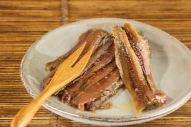 Arkaplanda tahta kaşık olan bir tabak balık, yakın çekim.