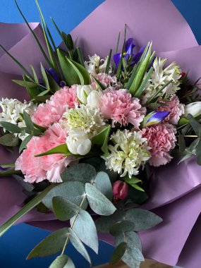 Güzel bir buket pembe ve beyaz lale sümbüller, süsenler ve yeşil okaliptüs içeren kabarık karanfiller dekoratif mor kağıda sarılı.