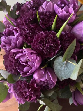 Güzel bir demet leylak lale ve yeşil okaliptüslü kabarık karanfiller.