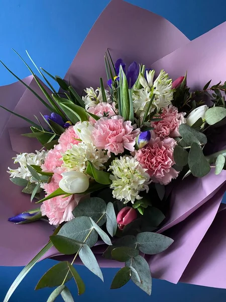 stock image A beautiful bouquet of pink and white tulips, hyacinths, irises and fluffy carnations with the addition of green eucalyptus, packed in decorative purple paper