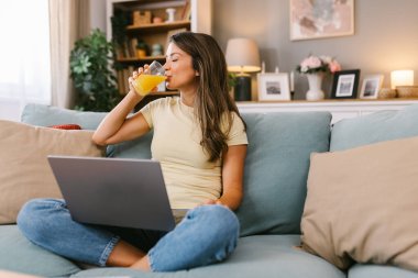 Kanepede oturmuş meyve suyu içen güzel bir kadın.