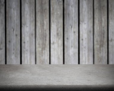Bulanık ahşap duvarın önündeki boş beton masa. Ürün görüntüleme, sunum modellemeleri, yiyecek fotoğrafçılığı veya kopyalama alanı olan tasarım şablonları için ideal.