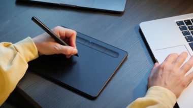 Moda tasarımcısı dijital tablete çizim yapıyor. Tabletle illüstrasyon çizerken kadın eli elektronik kalem kullanıyor. Çizim tasarımcısı stil kullanarak çalışıyor ve resim çiziyor