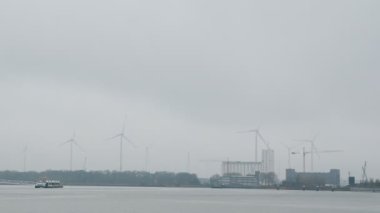 Antwerpen 'deki yel değirmenleri. Temiz yeşil enerji sürdürülebilirliği. Yenilenebilir kaynaklar çevre elektrik gücü. Yel değirmenlerinde dönen beyaz bıçaklar. Endüstriyel kasabanın arkasında dönen rüzgar türbinleri