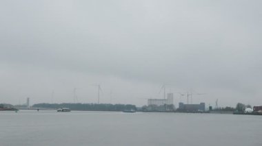 Antwerpen 'de endüstriyel kısmı ve arka planında yel değirmenleri olan bir kanal var. Antwerp, Belçika 'daki liman bölgesinde. Antwerpen 'de endüstri. Engin Scheldt Nehri ve Antwerp liman binaları