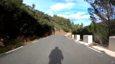 Güzel dağ yolundan inen bisikletçi silueti. Profesyonel bisikletçi dağ kıvrımlı yolundan aşağı iniyor. Sağlıklı spor yaşam tarzı. Yokuş aşağı bisikletle inen bir adam. Spor konsepti