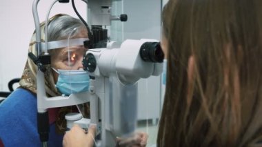 Optometrist checking eyesight to elderly woman in laboratory. Female pensioner doing eye test and vision correction. Pharmacy concept. Ophthalmology treatment. Woman checking her eyes in clinic