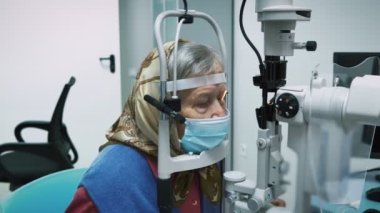 Yaşlı bir kadın için göz kontrolü yapan oftalmoloji uzmanı, fosfor makinesinden bakıyor. Modern laboratuvarda görme testi yapan yaşlı bir insan. Göz doktoruyum. Göz görüşümü kontrol ediyorum.