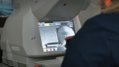 Ftalmolog, modern tıbbi ekipmanlar kullanarak görme yetisini ölçüyor ve inceliyor. Oftalmoloji tedavisi. Doktor optometrist görüşü özel monitörden kontrol ediyor.