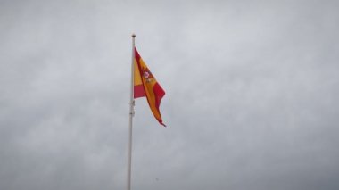 İspanya 'nın ulusal bayrağı rüzgarda dalgalanıyor. Bulutlu gökyüzüne karşı bayrak direğinde dalgalanan İspanyol bayrağı