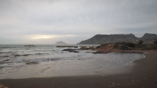コスタ ブランカの美しい海岸に沈む夕日 大きな海の波が飛び散って白い泡を作り出す 大きな波と砂浜がある絵のような海辺 美しい雲海 — ストック動画
