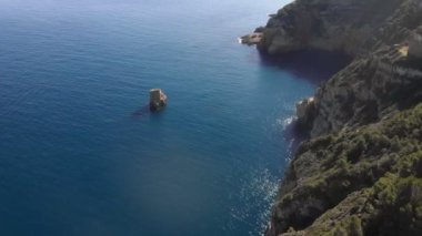 Kayalıkları ve yeşil ağaçları olan güzel kayalık kıyı şeridi. Berrak mavi suyla sakin bir deniz. Akdeniz sahili kıyısı. Calpe, İspanya. Resimli doğa. Güneşli bir günde manzara.