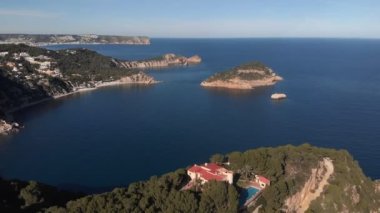 İspanya 'nın kayalık kıyı şeridinde yüzme havuzu olan lüks bir villa. Hava görüntüsü. Kayalık deniz kıyıları ve sakin deniz yüzeyi ile şaşırtıcı doğa manzarası. Yeşil tepeli inanılmaz bir deniz manzarası