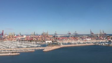 Valencia Limanı 'nda bir sürü kargo konteynırı, demirli yatlar ve gemilerle. Valencia, İspanya 'daki limanda büyük vinçler kargo taşıyıcı konteynırları yüklüyor. Kargo taşımacılığı