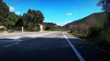Yeşil dağ kanyonu ve vadi boyunca asfalt yol. Yolun aşağısında bisiklete binen profesyonel bir bisikletçi. Bisiklet sporu aktivitesi. Triatlon konsepti