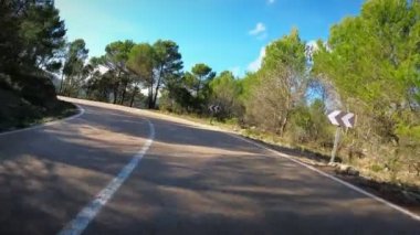 Güzel doğal kıvrımlı asfalt yol, POV araç sürüş. Akdeniz kıyısındaki tepe manzaralı araba yolu mavi gökyüzü ve beyaz bulutlar arka planda. Gündüz vakti dağların arasından yol