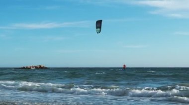 Rüzgarlı bir günde, deniz dalgaları üzerinde uçan genç bir adam. Su ekstrem spor. Aktif yaşam tarzı. Sporcu uçurtma dalgalarda sörf yapıyor. Spor etkinliği