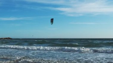 Man kitesurfing on huge waves at windy day. Young active people windsurfing and kitesurfing in Mediterranean Sea in Spain. Active lifestyle. Water extreme sport activity. Spending active time by sea