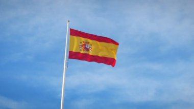 İspanyol bayrağı rüzgarla hareket etti, yaklaşın. İspanya 'nın ulusal bayrağı güçlü bir rüzgarla dalgalanırken bulutlar ve mavi gökyüzü arka planda