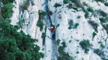 Young fit male rock climber fully equipped and wearing protective helmet climbing on cliff. Man alpinist ascending rocky mountain. Extreme active sport. Dangerous sports activity
