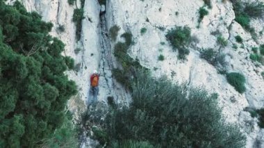 Korumalı miğferli kayalık kayalıklara tırmanan erkek kaya tırmanışçısı. Dağcı tebeşir torbası kullanarak dikey kaya duvarına tırmanıyor. Olağanüstü bir spor. Aktif spor. Kaya tırmanıcısı