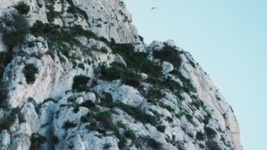 Kaya dağına tırmanan koruyucu miğferli, donanımlı bir kadın. Kaya tırmanıcısı. Olağanüstü bir spor. Aktif spor. İspanya 'nın Calpe kentindeki Penon de Ifach dağına tırmanan turist