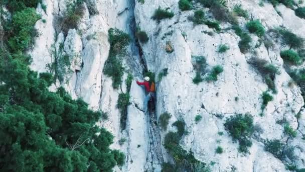 年轻健康的男性攀岩者装备齐全 头戴防护头盔爬上悬崖 人类的爬山者爬上了岩石山 非常积极的运动 危险的体育活动 — 图库视频影像
