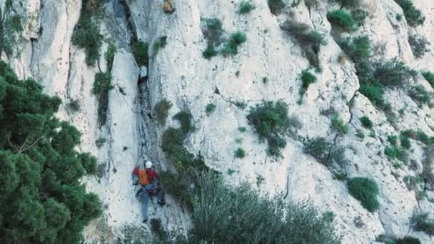 保護ヘルメットロープを使用してロックマウンテンクライミングの男岩クライマー 若いフィット男性登山岩の崖 極端なアクティブスポーツ 岩を登ろうとする登山家 — ストック動画