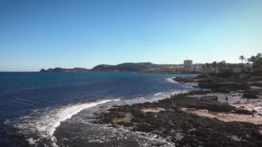 Coastline of Javea, Costa Blanca, Spain at sunny summer day. Beautiful seascape with rocky seashore and buildings on background. Amazing nature landscape