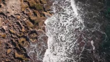 Big sea waves crashing on rocky seashore, splashing and creating white foam, top view. Amazing seascape. Rough sea waves crashing on rocks in Mediterranean Sea. Sea waves hitting rocks on beach