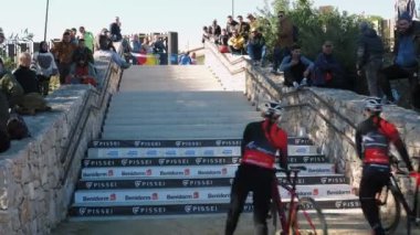 Cyclocross race, Benidorm, Spain, 22.01.23. Active sport concept. Pro female cyclists climbing upstairs on stairs during cyclocross bike race. Bike riders taking part in bike competition with barriers