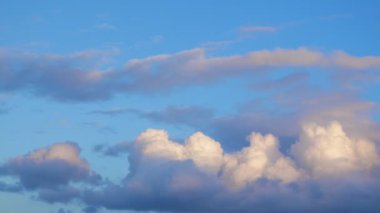 Dark evening clouds moving fast against blue sky. Time lapse of beautiful cloudscape with fluffy clouds against blue pink sky at sunset