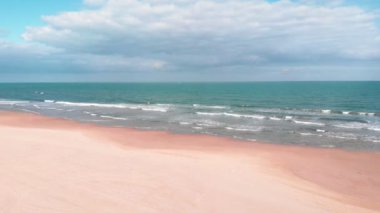 Wide empty sandy beach with turquoise sea waves in Costa Blanca, Spain. Amazing seascape with aquamarine sea water surface against blue sky. Tropical sand beach and seashore of Mediterranean Sea