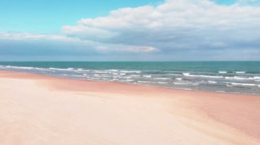 Sea waves breaking on sand beach. Seaside with turquoise sea waves and golden sandy beach. Coastline of Mediterranean Sea in Spain. Beautiful seashore with sea waves crashing on tropical sand beach