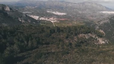 İspanya 'da yeşil çam ağaçları olan devasa kayalık dağlar. Dağ tepeleriyle çevrili turuncu ve mandalina tarlaları olan bir vadi. Güzel dağ manzarası. İspanya 'nın tabiat manzarası