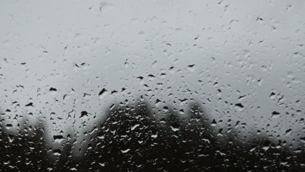 窓から雨が降った 秋の雨の天気 秋の抽象的な背景 曇った灰色の雨の日にガラス窓に滑り落ちる水 — ストック動画