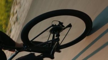 Bisiklet takımı, zincir ve kaset dönüyor. Bisiklet tekerleği dönüşü. Dikey video. Bisiklet ayakkabılarına sığan kadın kaslı bacaklar bisiklet pedalları çeviriyor. Spor konsepti. Triatlon ve bisiklet. Fitness etkinliği
